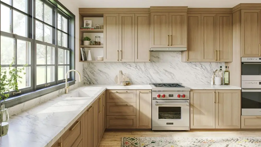 Modern light oak kitchen cabinets with Carrara marble countertops and brass hardware.